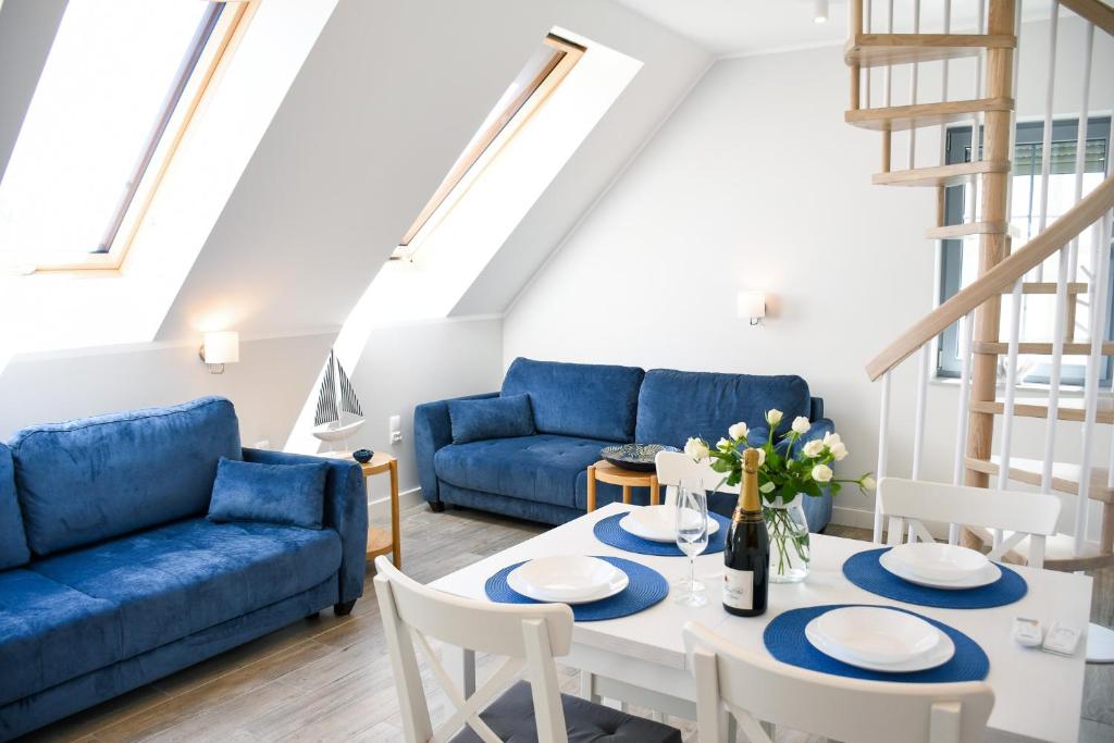 ein Wohnzimmer mit einem blauen Sofa, einem Tisch und Stühlen in der Unterkunft Apartamenty Wrzosowa in Dębki
