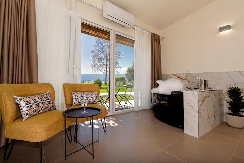 ein Wohnzimmer mit einem Tisch, Stühlen und einem Fenster in der Unterkunft Green Space Hotel in Ohrid