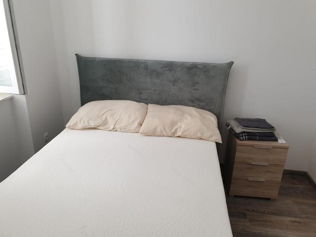 特里班的住宿－Apartmani Sain Tribunj，卧室配有白色床和灰色床头板