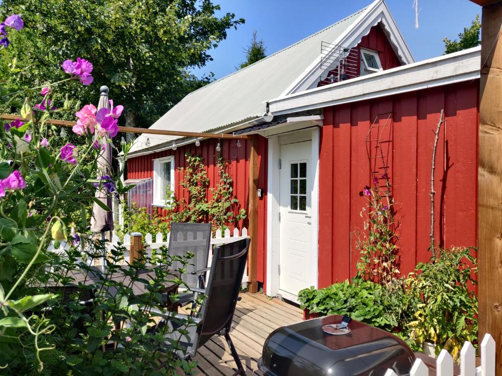 un capanno rosso con una porta bianca e fiori di Lillstugan - Centralt och havsnära i lugnt villområde a Falkenberg