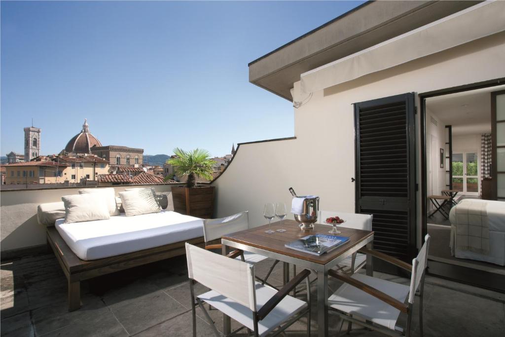 einen Balkon mit einem Bett, einem Tisch und Stühlen in der Unterkunft Gallery Hotel Art - Lungarno Collection in Florenz