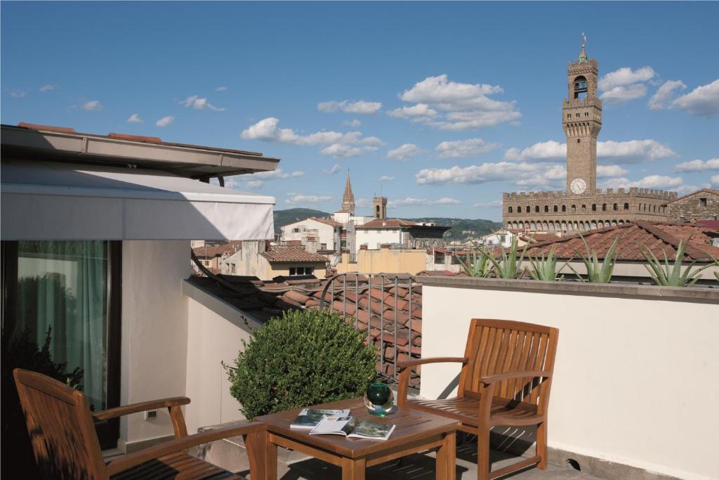 un balcone con tavolo, sedie e torre dell'orologio. di Gallery Hotel Art - Lungarno Collection a Firenze