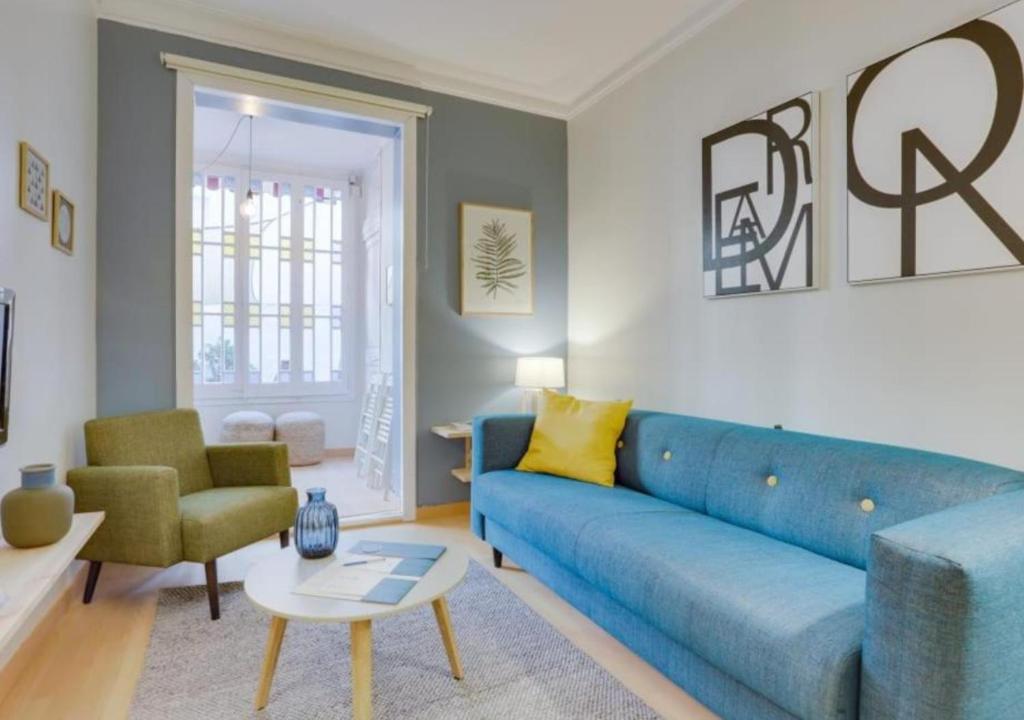 een woonkamer met een blauwe bank en een stoel bij Sweet Inn - Eixample Dreta in Barcelona
