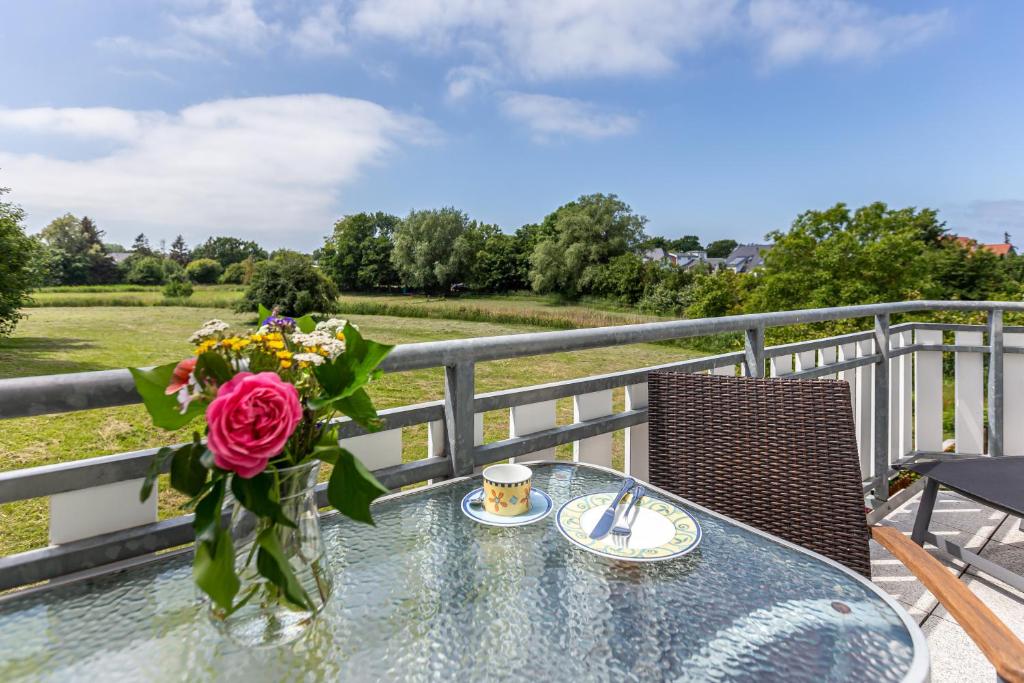 a table with a vase of flowers on a balcony at Wiesenblick in Ahrenshoop