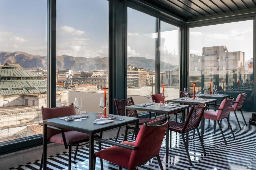 een restaurant met tafels, stoelen en ramen bij Hotel Plaza Opéra in Palermo