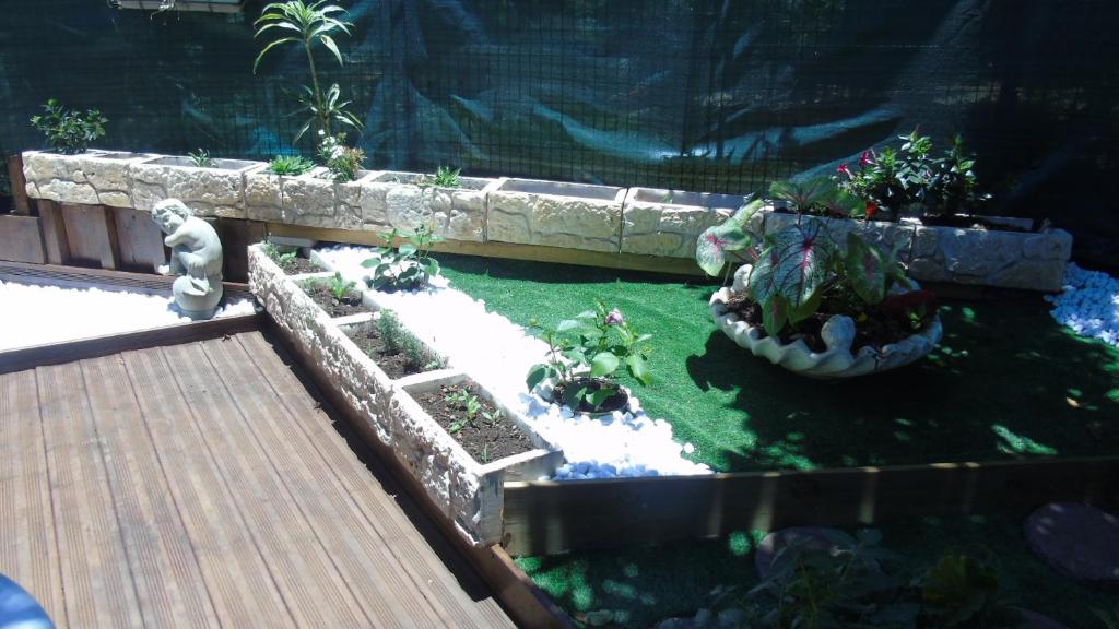 un jardin miniature avec des plantes et une terrasse en bois dans l'établissement la cigogne, à Petite Île