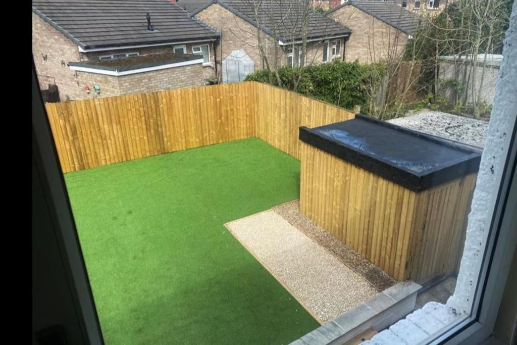 a backyard with a wooden fence and green grass at Modern 4 bed home, 30 minute walk from City Centre in York