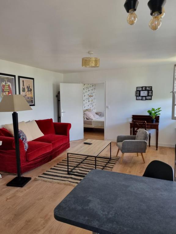 ein Wohnzimmer mit einem roten Sofa und einem Tisch in der Unterkunft Location saisonnière appartement situé à Saumur in Saumur