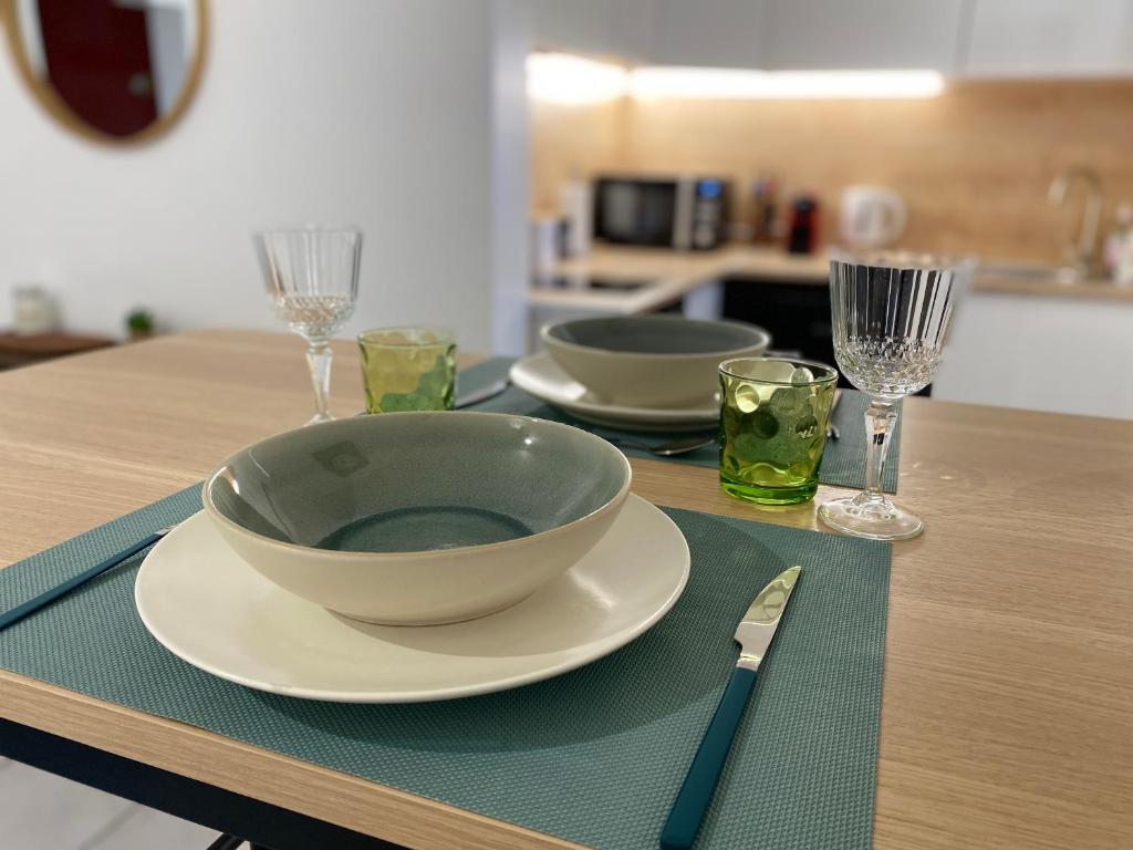 - une table avec un bol, des assiettes et des verres à vin dans l'établissement Superbe appartement 2 pièces, plein centre ville., à Montlhéry