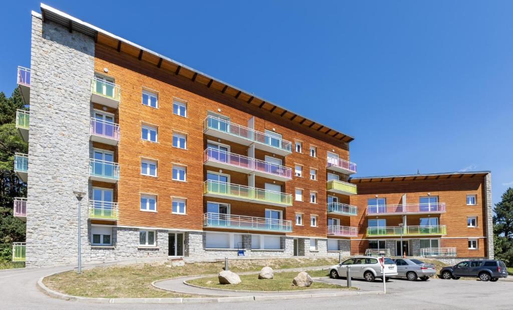 un edificio de apartamentos con coches estacionados frente a él en Panoramic Campus, en Font-Romeu-Odeillo-Via