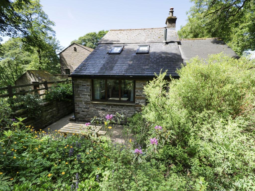 a small stone house in the middle of a garden at Bothy in Alston