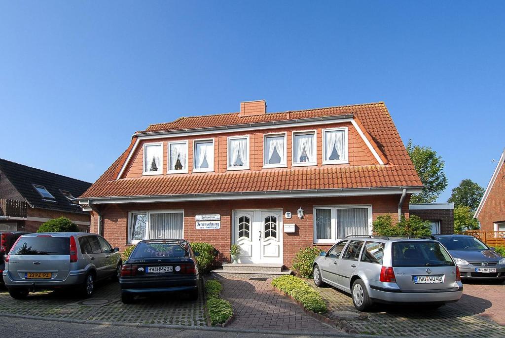 two cars parked in front of a brick house at Friesenmeer Ferienwohnung Eins in Bensersiel