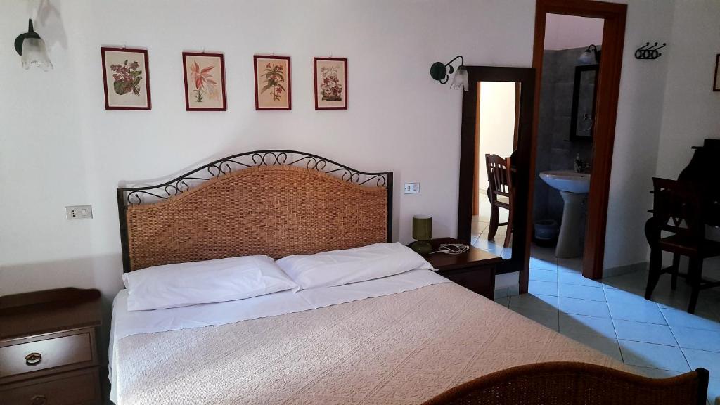 Villagrande StrisailiにあるFattoria Nuraghe Murtarbaのベッドルーム1室(大型ベッド1台、木製ヘッドボード付)