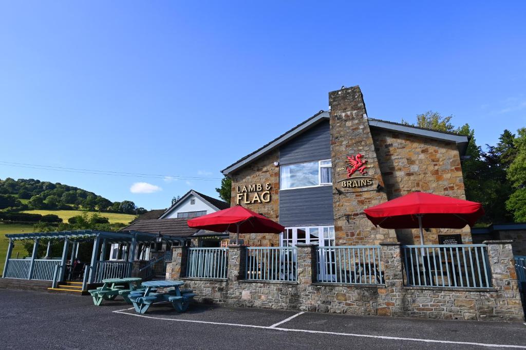 un restaurante con sombrillas rojas delante de él en Lamb & Flag Inn en Abergavenny