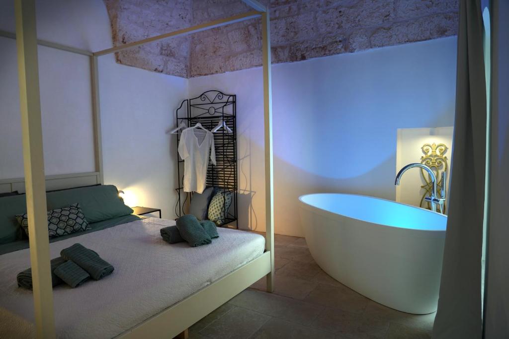 a bedroom with a tub and a bed with towels at Il Biancospino - graziosa Dimora con VASCA in CAMERA in Ostuni