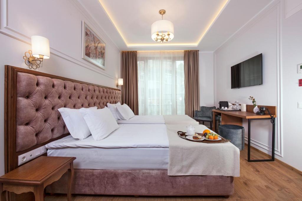 a hotel room with a large bed and a table at Villa Flavia Heritage Boutique Hotel in Plovdiv