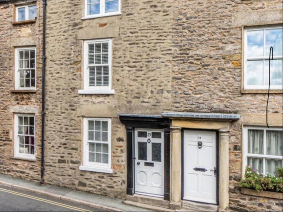 a brick building with white doors and windows at The Cottage on Fairbank - Kirkby Lonsdale in Kirkby Lonsdale