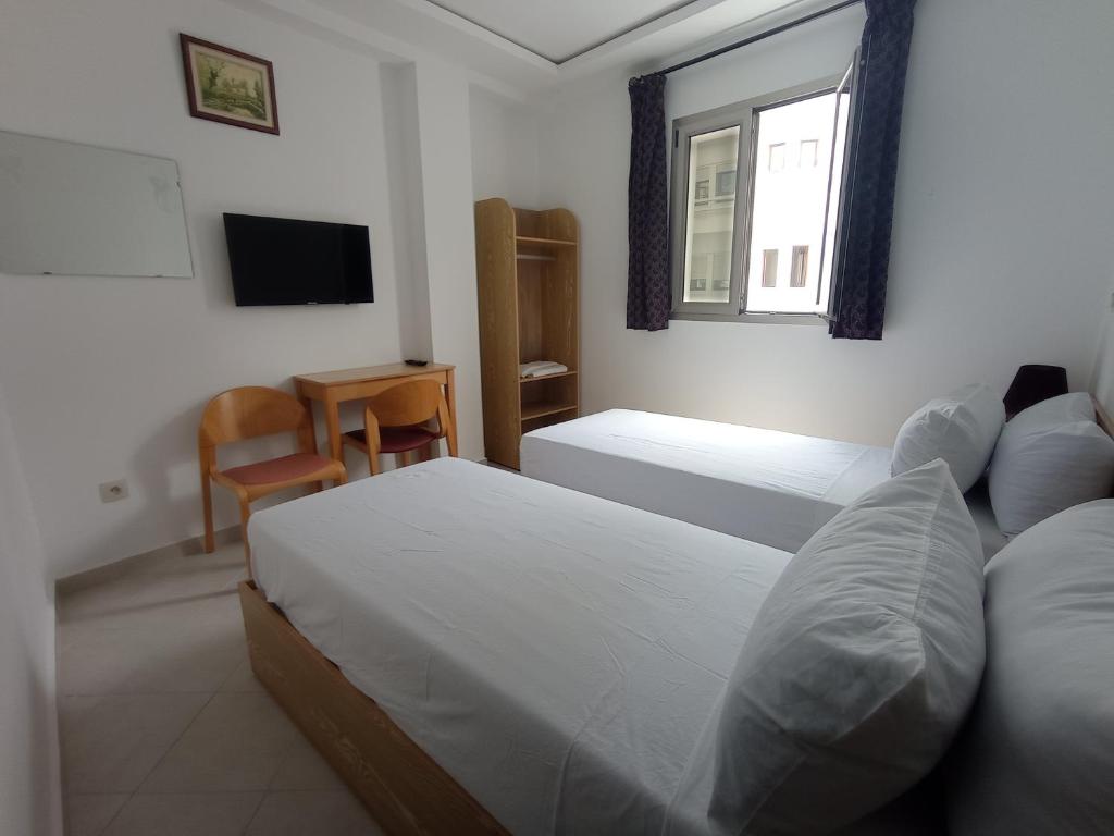 a bedroom with two beds and a tv and a window at HOTEL CASTIYA in M'diq