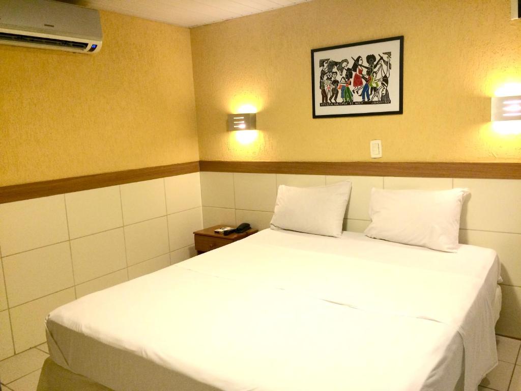 a hotel room with a white bed and white walls at Hotel Veraneio in Recife