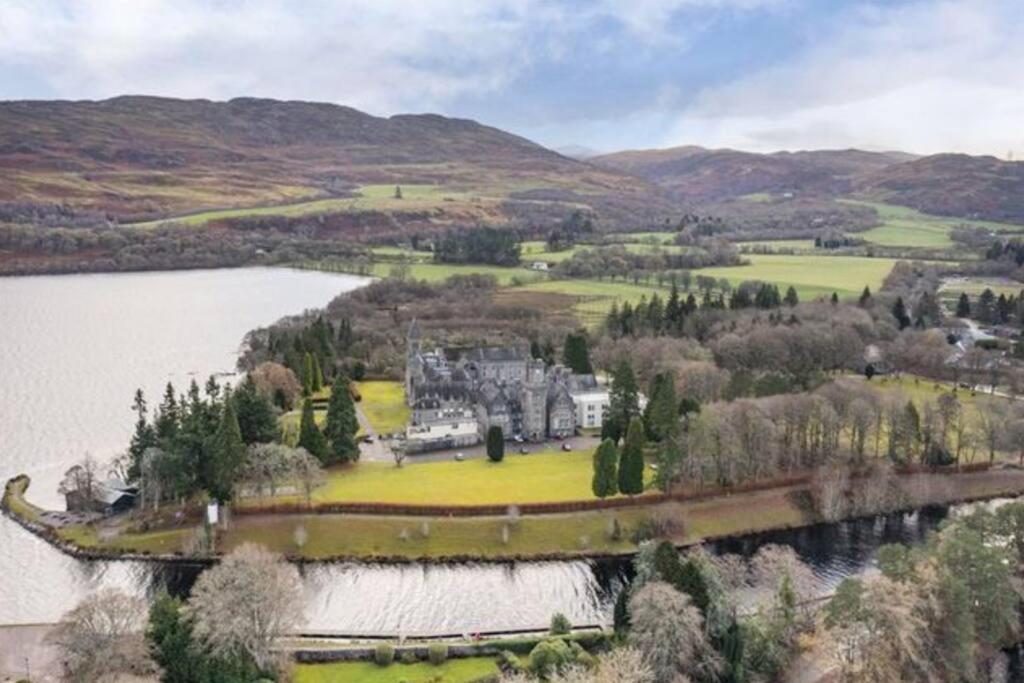 an aerial view of a mansion on an island in a lake at 3 BR Luxury Apt at Highland Club - Fort Augustus in Fort Augustus