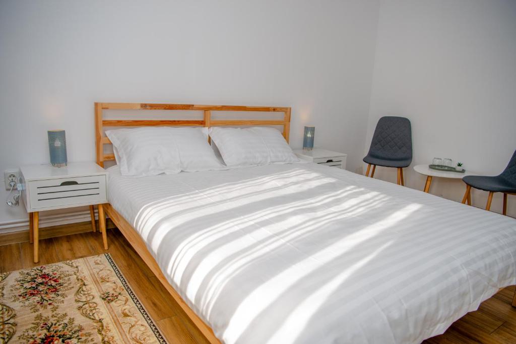 1 Schlafzimmer mit einem großen weißen Bett mit 2 Stühlen in der Unterkunft Family House Pristol in Pristol