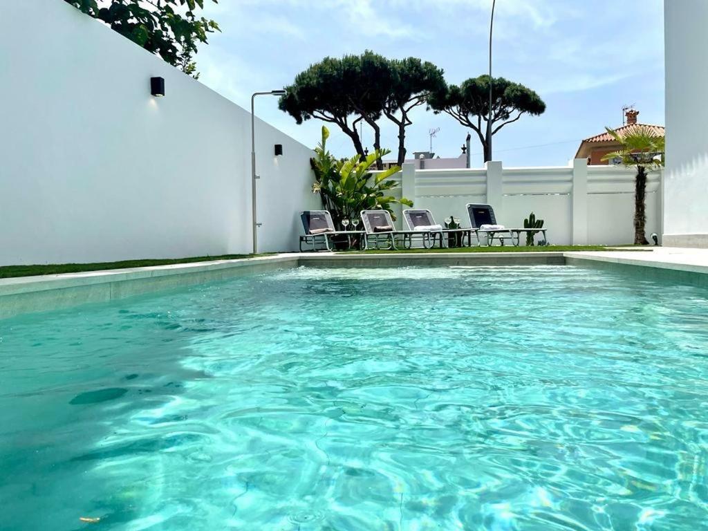 a swimming pool with blue water in a house at VILLA PIMIENTA, Chalet de lujo a 100 metros del mar in Chiclana de la Frontera
