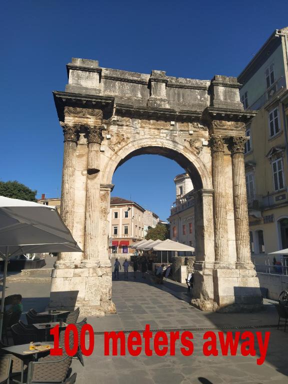 an arch in a city with the words meters away at Roman Arch- low budget doublebed room in top center in Pula