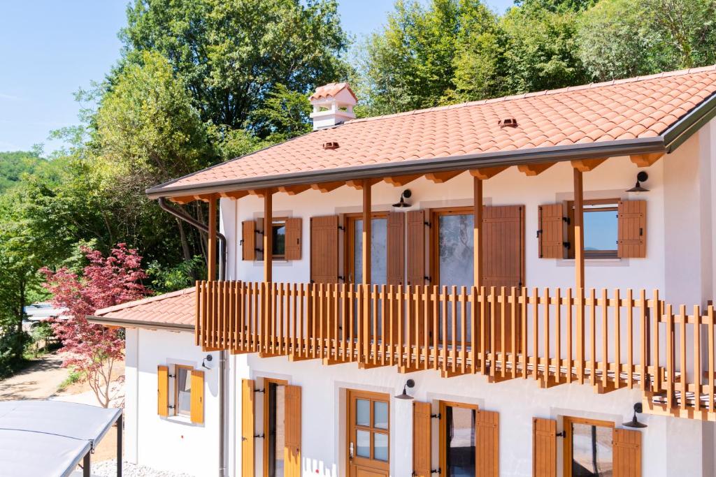 a house with a wooden balcony and trees at Tenuta Della Casa Wine & Rooms - La Pausa del Collio in Cormòns