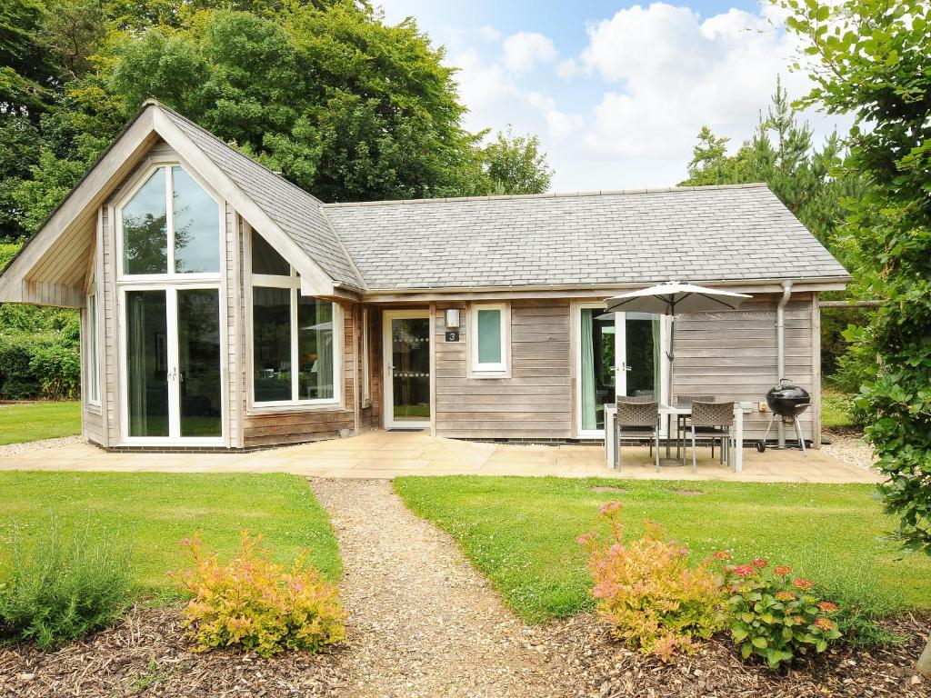a tiny house with a porch and a patio at Swandown, 3 Blackdown in Chard