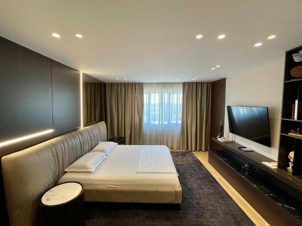 Luxury Lake View Duplex with Indoor Fireplace في شكودر: غرفة فندقية بسرير وتلفزيون بشاشة مسطحة