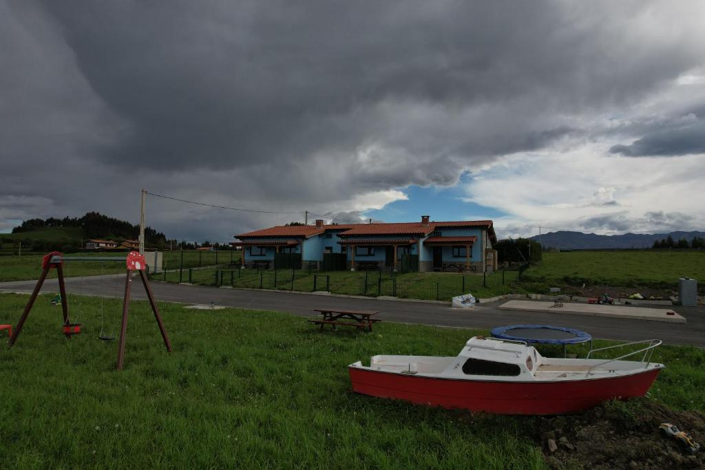 a boat sitting on the grass in front of a house at Apartamentos Rurales Miramar in Pimiango
