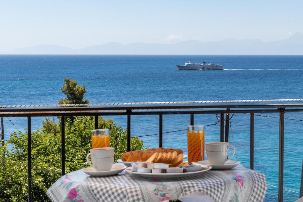 una mesa con pan y bebidas en un balcón con vistas al océano en Stafylos Rooms, en Stafylos