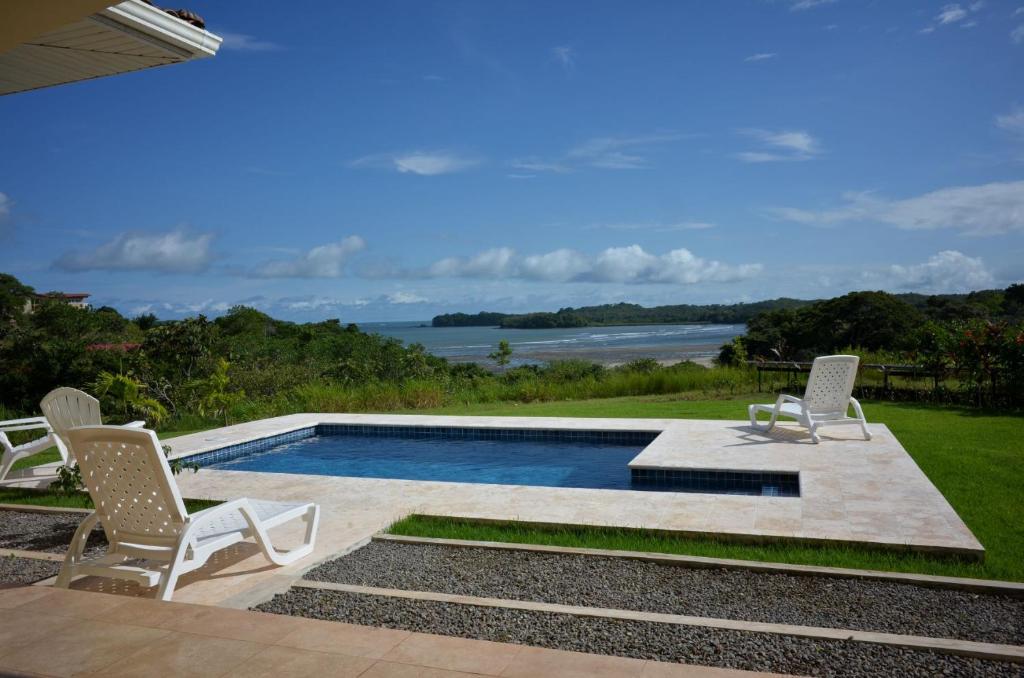 een zwembad met stoelen en uitzicht op het water bij Casa Tanamera in Boca Chica