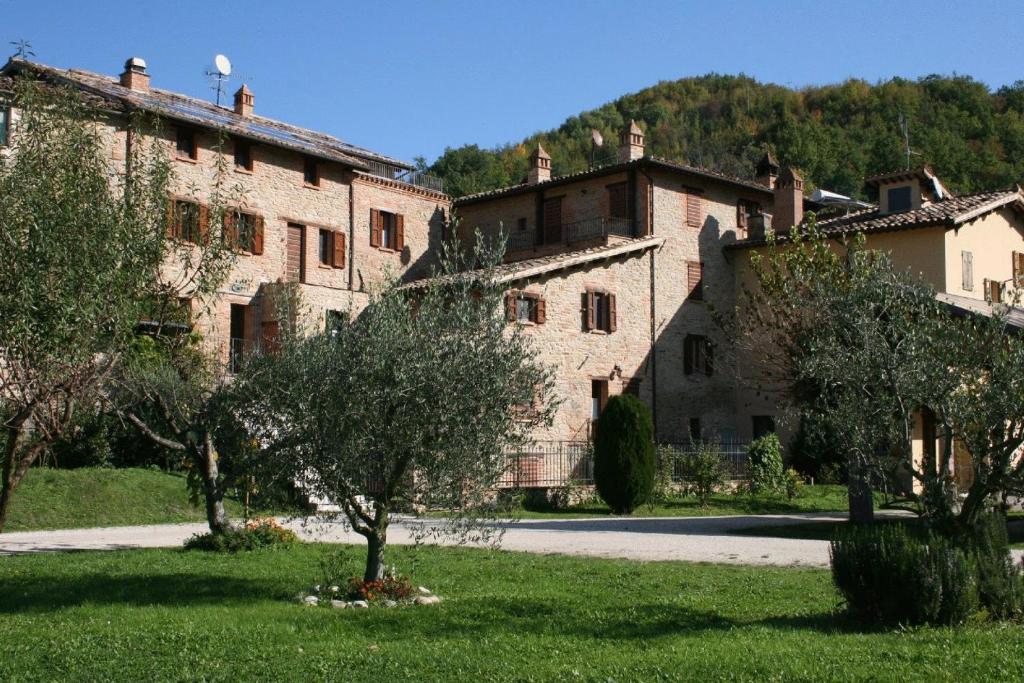 un vieux bâtiment en pierre avec des arbres devant lui dans l'établissement Agriturismo Le Selve, à Comunanza