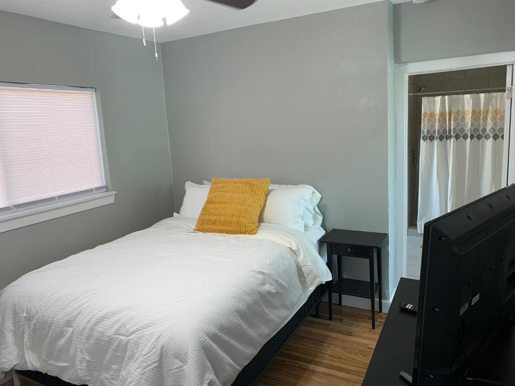 a bedroom with a bed with a yellow pillow and a tv at Comfortable Suite with private entrance & private bathroom in El Paso