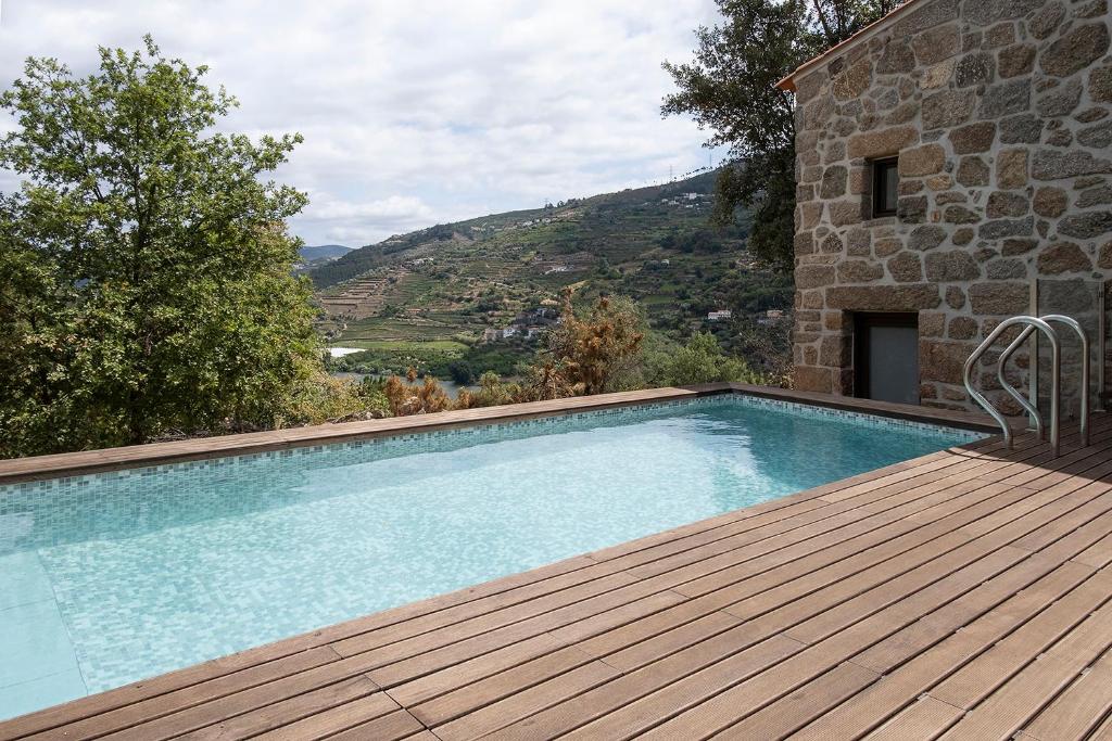 einen Pool auf einer Holzterrasse neben einem Gebäude in der Unterkunft Quinta de São Pedro in Barrô