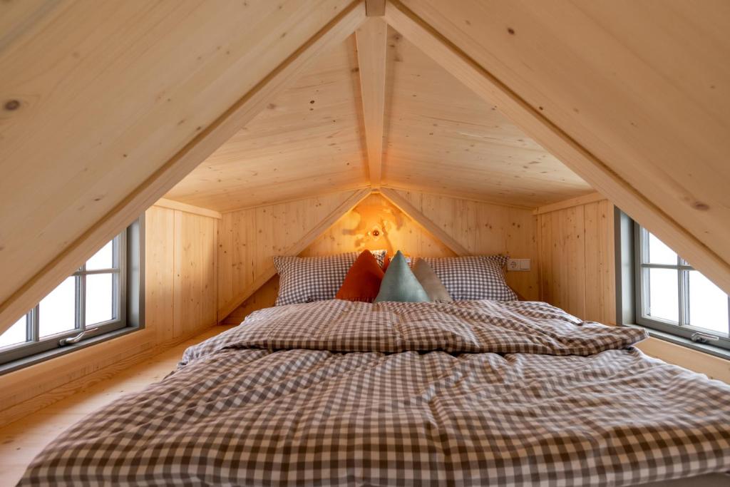 Cama en habitación de madera con ventanas en Grimmwald Tiny House en Calden