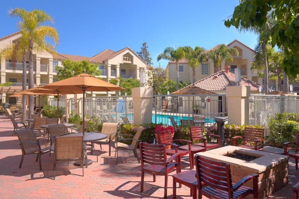 um pátio com mesas e cadeiras e uma piscina em Hyatt House LAX Manhattan Beach em El Segundo