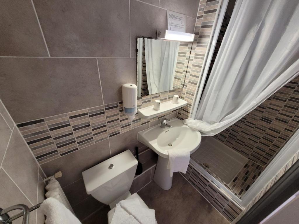 a bathroom with a sink and a toilet and a mirror at Le Cérétan Hôtel in Céret
