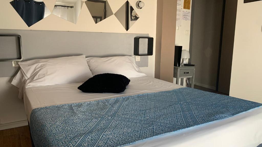 a bed with a black hat sitting on top of it at Le Cérétan Hôtel in Céret