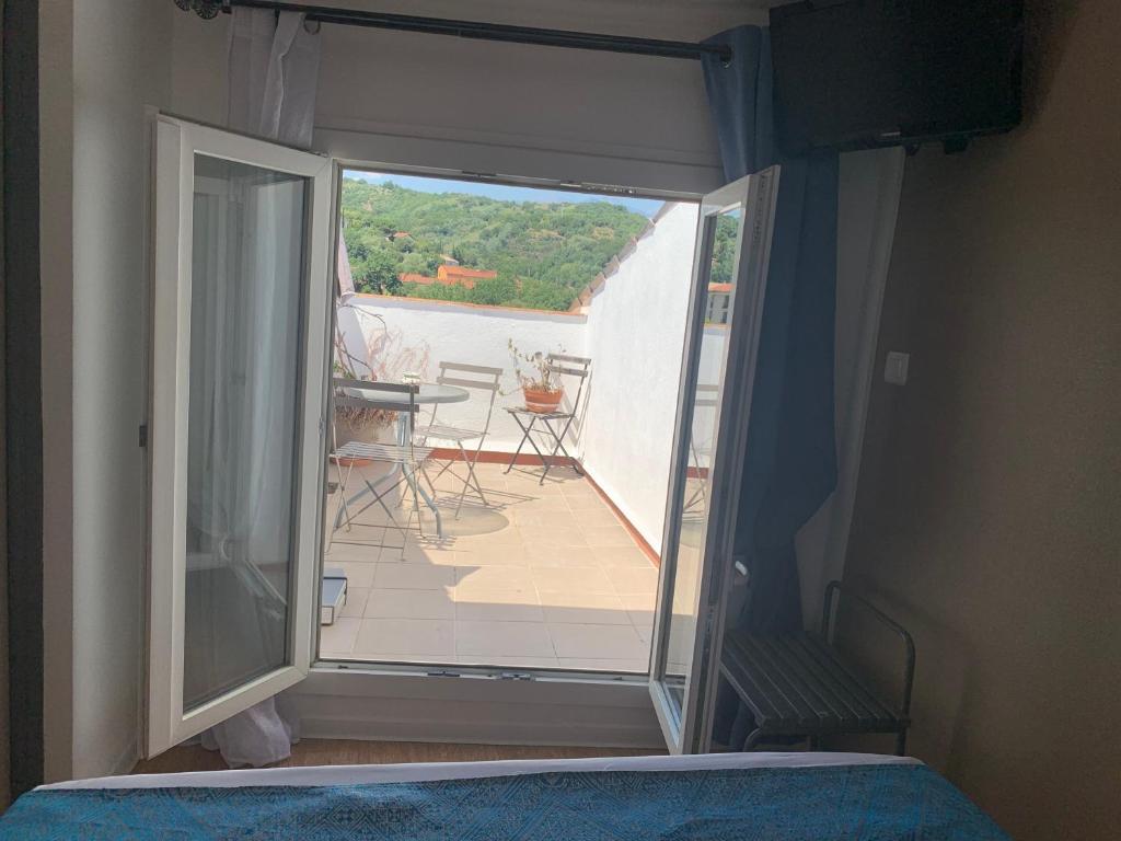 a bedroom with a door open to a balcony at Le Cérétan Hôtel in Céret