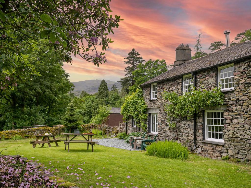 a stone house with a picnic table in the yard at Little How in Ambleside