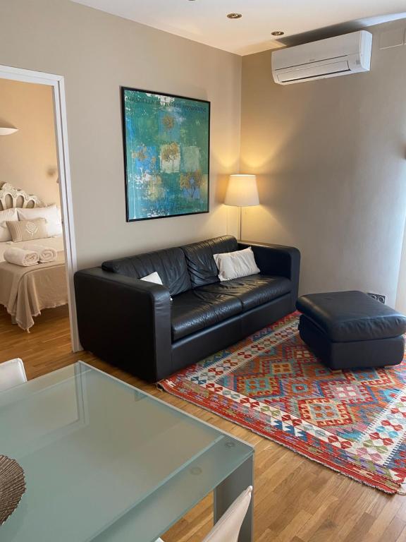 un soggiorno con divano in pelle nera e tappeto di Petit Rosselló a Barcellona