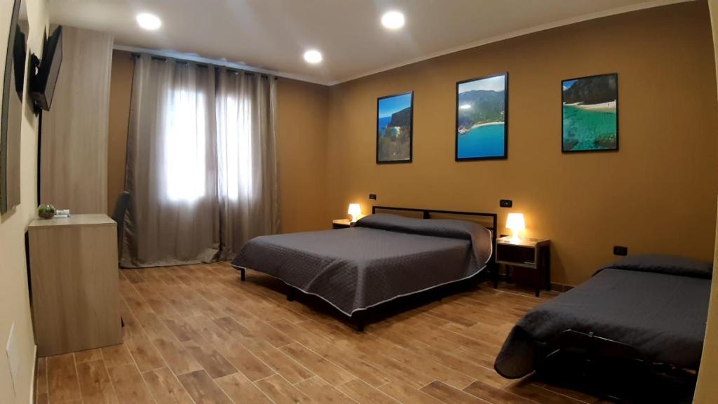 1 dormitorio con 2 camas y pinturas en la pared en La Casa D' Ogliastra tra mare e terra, en Tortolì