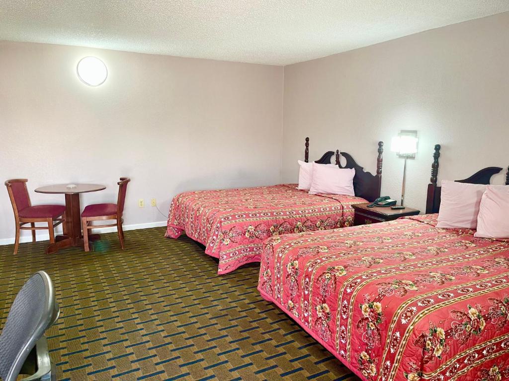 um quarto de hotel com duas camas e uma mesa em Bradbury Inn em Big Spring