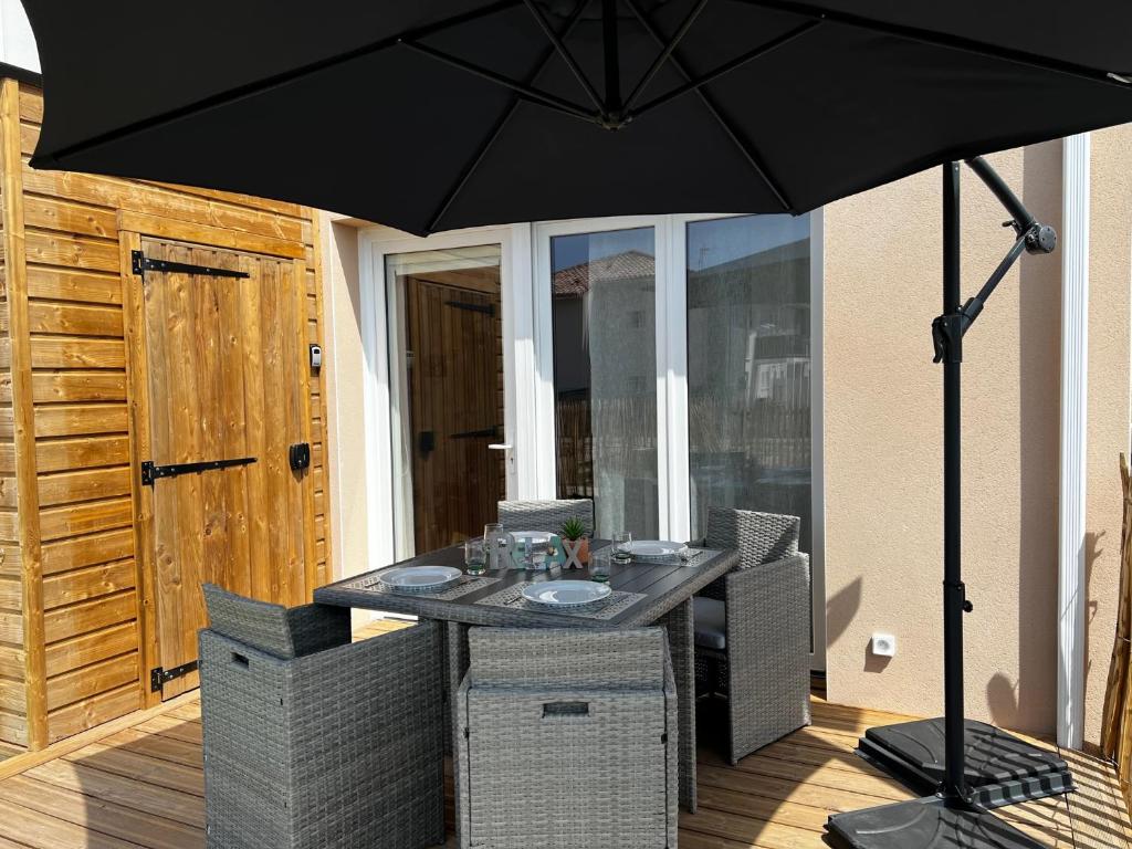 a table and chairs under an umbrella on a patio at La Cabane de Mimizland ~ 10 min à pied de l'océan in Mimizan