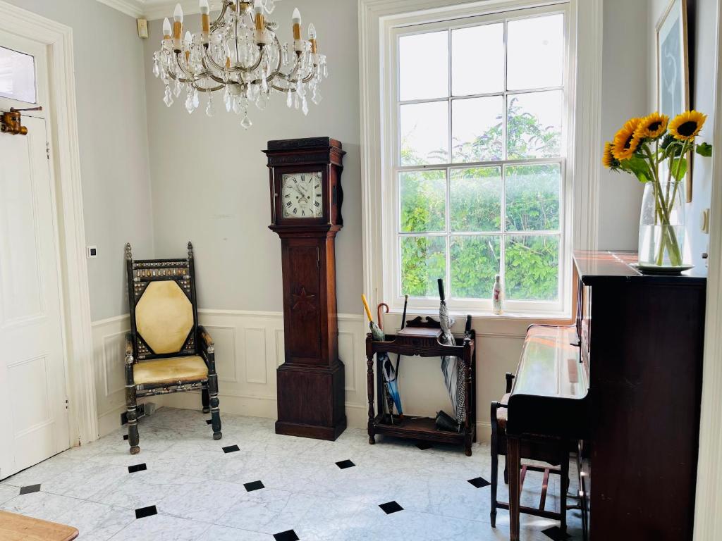 um quarto com um relógio avô e uma cadeira em Beautiful Private 2 Bedroom Suite in Mansion Home with Free Parking em Brighton & Hove