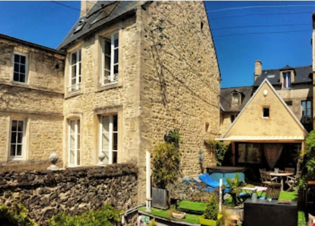 an old stone building with a patio in front of it at Le Clos de la Chapelle Bayeux in Bayeux