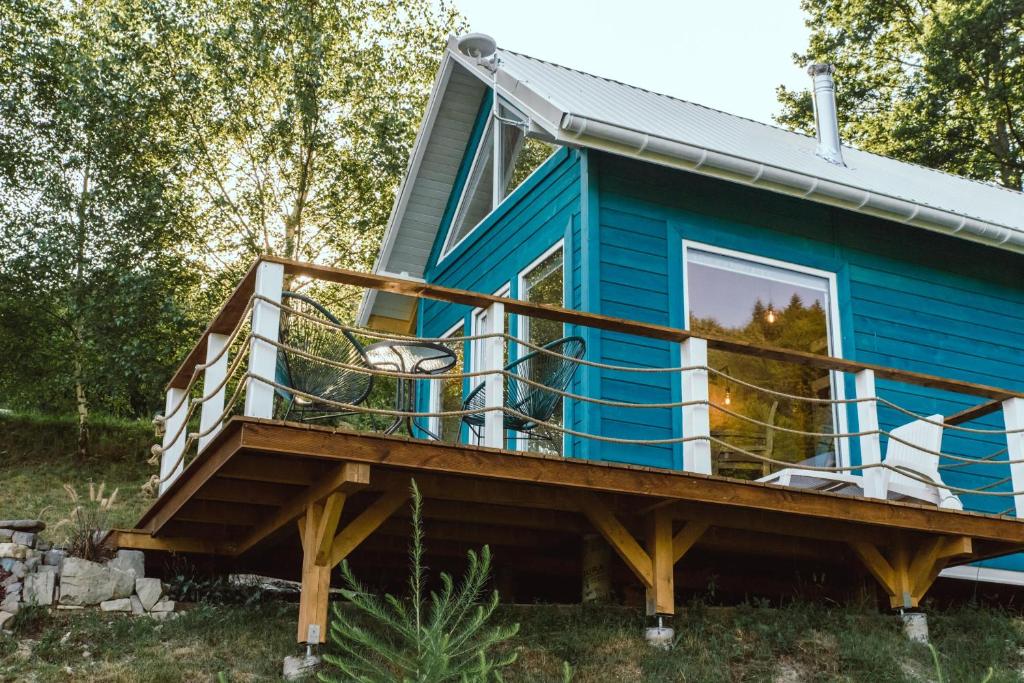 ein kleines blaues Haus mit einer großen Terrasse in der Unterkunft Lazurowe Love - domek na odludziu z widokami in Jaszczurowa