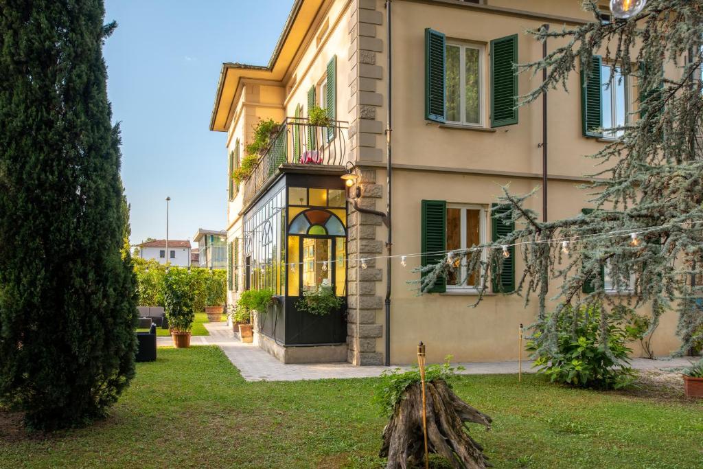 un bâtiment avec des fenêtres vertes à volets et une cour dans l'établissement Villa Romantica Wellness & SPA, à Lucques